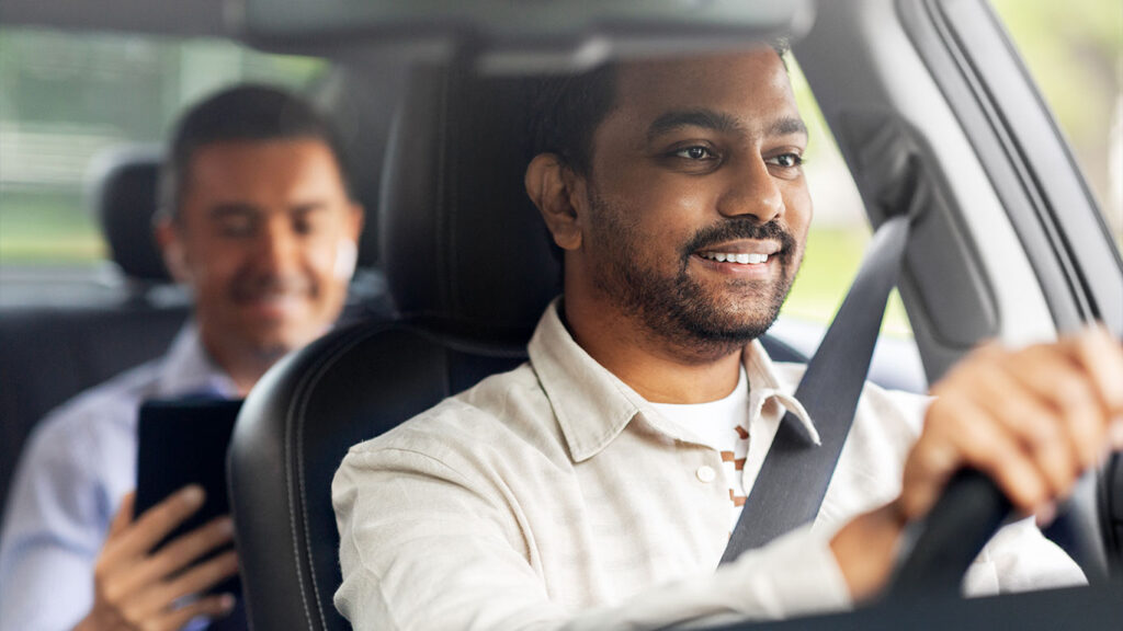 Photograph of Indian male driver driving car with passenger