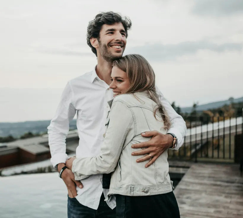 smiling couple hugging on deck infinity pool